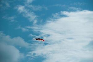 Colored paper kite like rainbow on blue sky background. Kites are flown along the beach. Beautiful colors in the air photo