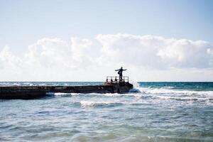 a portrait of a young man on a pier, waves splashing and crashing against the pier photo