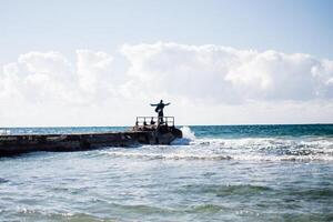 a portrait of a young man on a pier, waves splashing and crashing against the pier photo