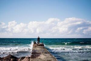 a portrait of a young man on a pier, waves splashing and crashing against the pier photo