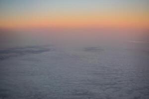 a dawn above the clouds through the porthole photo