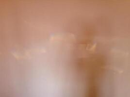 Blurry abstract peach colored background with patches of reflected light. photo