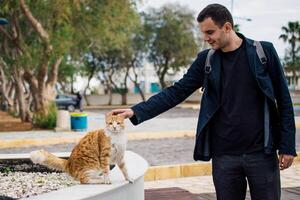 a man with backpack pet red stray cat photo