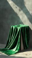 Emerald velvet fabric draped over cube podium in sunlight, artistic textile concept photo