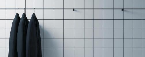 Three black suits hanging on a tiled wall photo