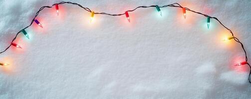 Colorful string lights on fresh snow background, winter holiday concept photo