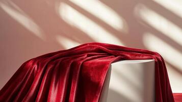 Red velvet fabric draped over a white cube podium with soft light and shadows, minimalist elegance concept photo