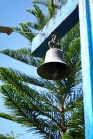 a bell hanging from a pole with a tree in the background photo