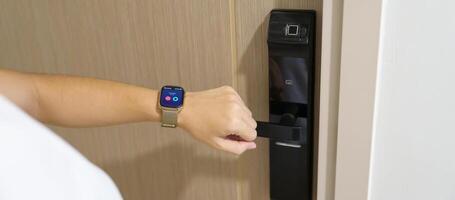 Hand using smartwatch for open digital door lock at home or apartment. NFC Technology, Fingerprint scan, keycard, PIN number, smartphone, electrical and contactless lifestyle concepts photo