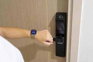 Hand using smartwatch for open digital door lock at home or apartment. NFC Technology, Fingerprint scan, keycard, PIN number, smartphone, electrical and contactless lifestyle concepts photo