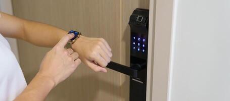 Hand using smartwatch for open digital door lock at home or apartment. NFC Technology, Fingerprint scan, keycard, PIN number, smartphone, electrical and contactless lifestyle concepts photo