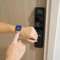 Hand using smartwatch for open digital door lock at home or apartment. NFC Technology, Fingerprint scan, keycard, PIN number, smartphone, electrical and contactless lifestyle concepts photo
