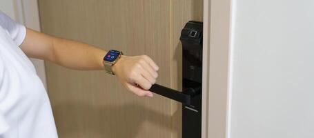 Hand using smartwatch for open digital door lock at home or apartment. NFC Technology, Fingerprint scan, keycard, PIN number, smartphone, electrical and contactless lifestyle concepts photo