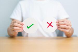 Woman show Wrong and Right symbol paper. True and false, accept and rejected, evaluation, Vote, Poll, Yes or No and Survey concepts photo