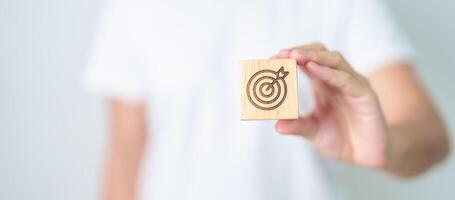 hand hold dartboard block with business goal, strategy, target, mission, action, objective, aim and success concept photo