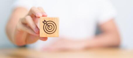 hand hold dartboard block with business goal, strategy, target, mission, action, objective, aim and success concept photo