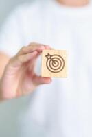 hand hold dartboard block with business goal, strategy, target, mission, action, objective, aim and success concept photo