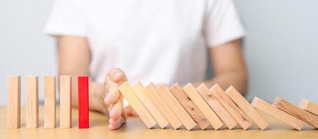 Hand stop falling wood domino blocks on table. Crisis, fall Business, Risk management, Economic recession, Strategy and solutions concept photo