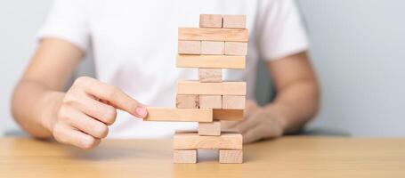 hand pulling wooden block tower on table. Business planning, Risk Management, Solution, leader, strategy, Crisis, falling Business, and Economic recession concept photo