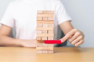 hand pulling wooden block tower on table. Business planning, Risk Management, Solution, leader, strategy, Crisis, falling Business, and Economic recession concept photo