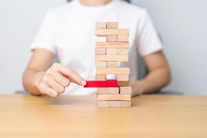 hand pulling wooden block tower on table. Business planning, Risk Management, Solution, leader, strategy, Crisis, falling Business, and Economic recession concept photo