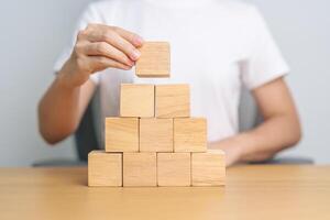 hand placing or pulling wooden block on the building. Business planning, Risk Management, Solution and strategy Concepts photo