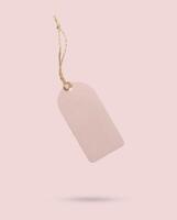 Blank price tag tied with string isolated on pink background photo