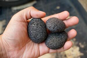 Three black lava rocks in a person's hand photo
