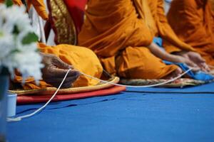 Selective focus on the hand of Buddhist holding the white rope while praying photo