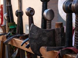 close up shot of a wooden rack with medieval combat weapons such as axes and swords photo