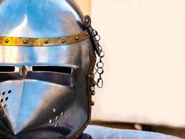 close up shot of a medieval metal helmet from one side and a blank white banner in the background. photo