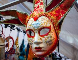 close-up of a red, white and gold mask for sale from the Venice carnival that recalls the figure of a jester photo
