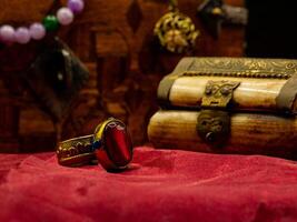 reproduction golden ring with ruby gem decorated medieval with an ivory casket on a red velvet table photo