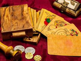deck of medieval italian board playing cards with a blank and white card, on the table along with coins and wooden card holder photo