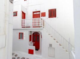 Whitewashed alley with stairs and colorful doors and windows in Mykonos, Greece. Traditional Cycladic architecture. photo