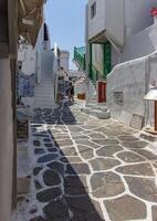 Whitewashed alley with stairs and colorful doors and windows in Mykonos, Greece. Traditional Cycladic architecture. photo