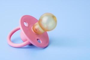 Orthodontic pacifier on a blue background. Pink baby pacifier photo