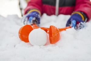 Device for sculpting snowballs in childrens hands on background of snow photo