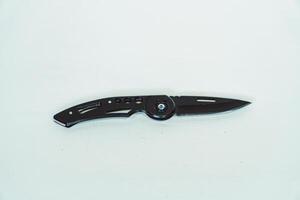Mini size folding knife of solid black color partially opened isolated on white background. Close-up view of a black folding knife used for various outdoor or survival activities photo