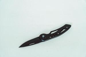 Mini size folding knife of solid black color partially opened isolated on white background. Close-up view of a black folding knife used for various outdoor or survival activities photo