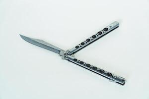 Partially open silver balisong or butterfly knife isolated on white background. Close-up of a sharp balisong knife or butterfly knife in various positions on a white background photo