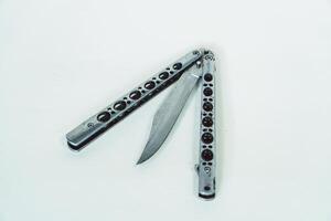 Partially open silver balisong or butterfly knife isolated on white background. Close-up of a sharp balisong knife or butterfly knife in various positions on a white background photo