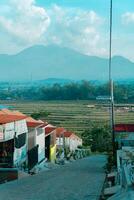 Residential area with beautiful views with a backdrop of green rice fields and mountains that look magnificent from a distance. Public housing complex on hills with sloping land with mountain views photo