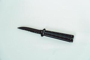Partially open matte black balisong or butterfly knife isolated on white background. Close-up of a sharp balisong knife or butterfly knife in various positions on a white background photo