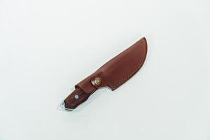 Close-up of a wooden handled adventure knife with a leather sheath. Pocket knife with a sharp stainless steel blade with a wooden handle, perfect for outdoor adventures and bushcraft activities photo