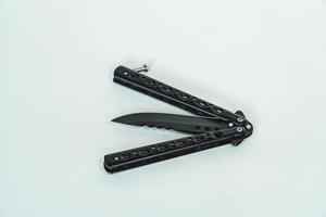 Partially open matte black balisong or butterfly knife isolated on white background. Close-up of a sharp balisong knife or butterfly knife in various positions on a white background photo