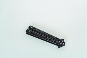 Partially open matte black balisong or butterfly knife isolated on white background. Close-up of a sharp balisong knife or butterfly knife in various positions on a white background photo