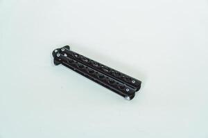 Partially open matte black balisong or butterfly knife isolated on white background. Close-up of a sharp balisong knife or butterfly knife in various positions on a white background photo