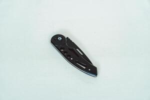 Mini size folding knife of solid black color partially opened isolated on white background. Close-up view of a black folding knife used for various outdoor or survival activities photo