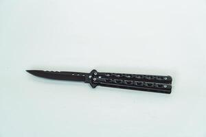 Partially open matte black balisong or butterfly knife isolated on white background. Close-up of a sharp balisong knife or butterfly knife in various positions on a white background photo